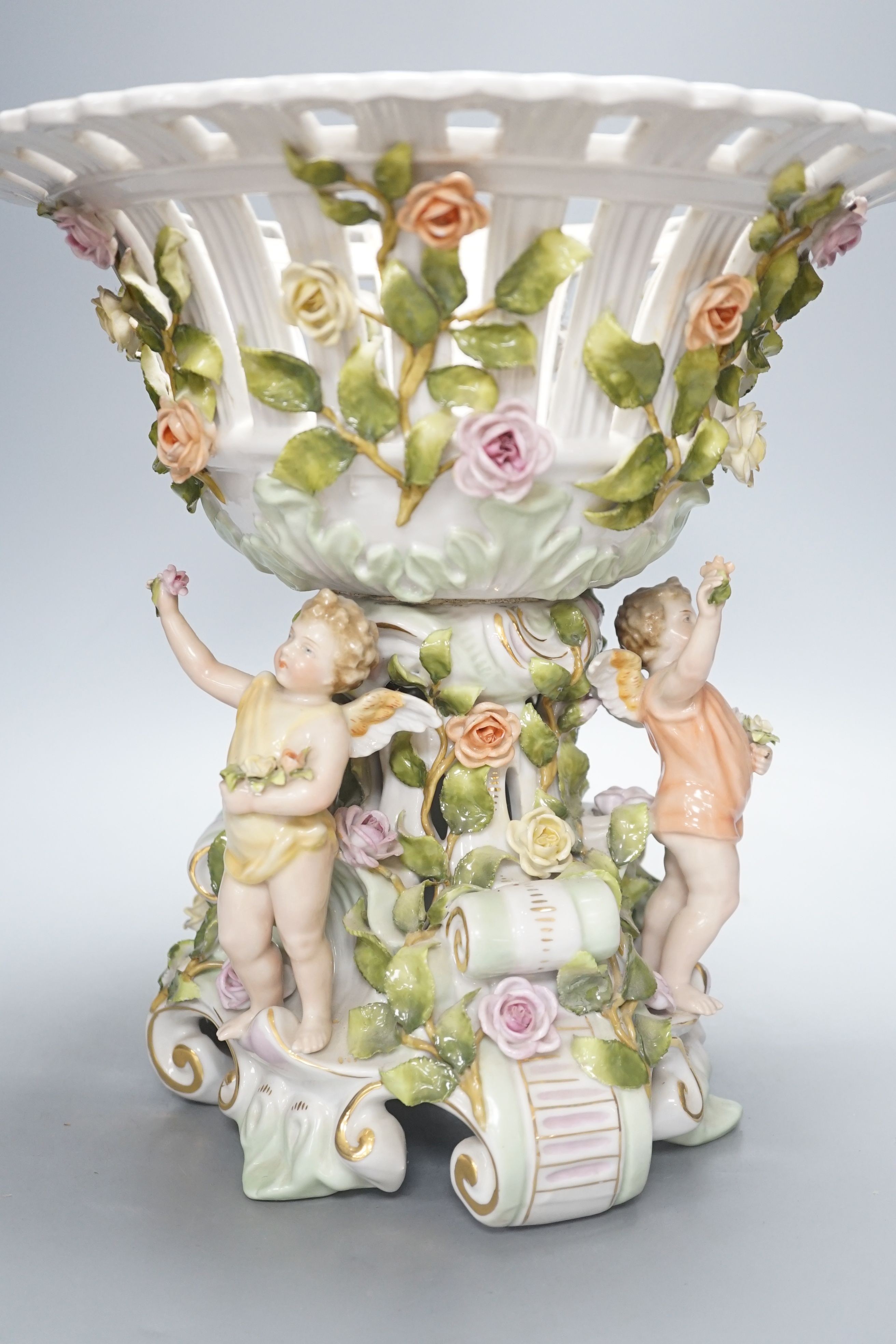 A German porcelain floral encrusted fruit stand, on a figural base, 30cm tall